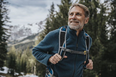 Portrait of smiling man standing against trees in winter