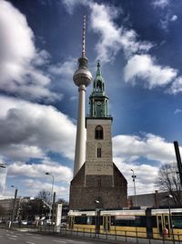 Low angle view of communications tower against cloudy sky