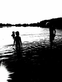 Silhouette people in water at sunset