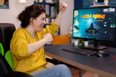 Side view of young woman using laptop at home