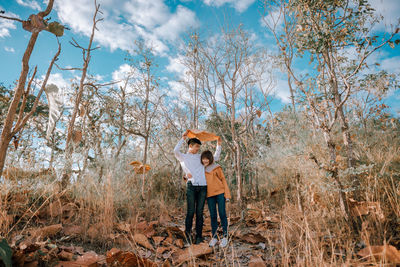 Friends standing by plants against trees