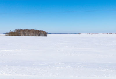 Scenic view of snow covered land against clear blue sky