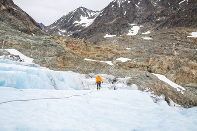 Rear view of person hiking on glacier against mountain
