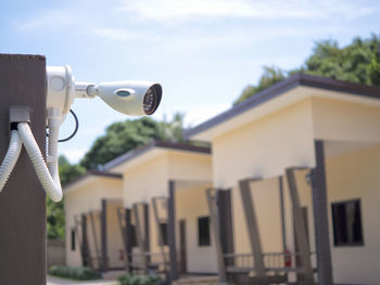 Close-up of security camera against buildings