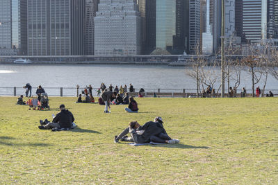 People relaxing in park against buildings in city