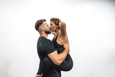 Side view of young couple kissing against white background