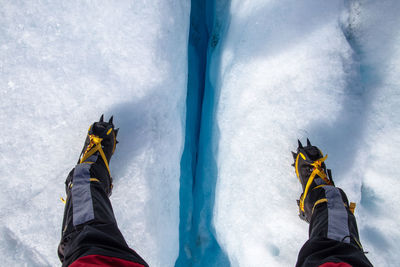 Low section of person wearing crampon shoe on snowy field