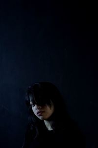 Portrait of a young woman over black background