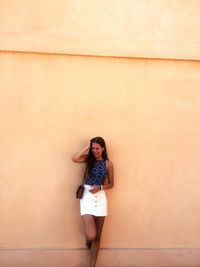 Full length of woman standing against wall