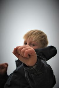 Portrait of boy boxing against clear sky