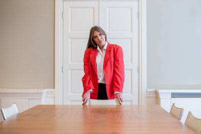 Portrait of young woman standing by table