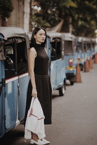 Side view of woman standing on street in city