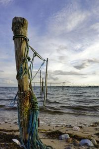 View of wooden post on beach against sky