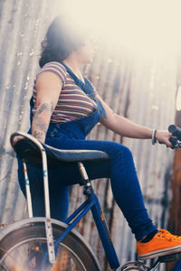 Woman riding vintage bicycle against sun