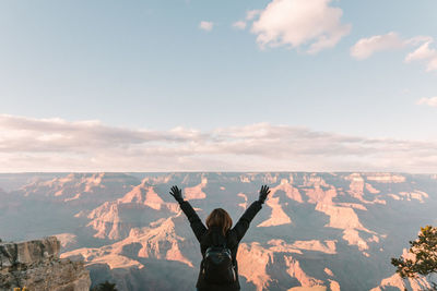 Woman with arms raised against sky