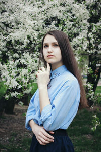 Portrait of beautiful young woman standing against plants