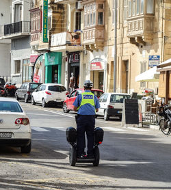 Rear view of man riding bicycle on city street