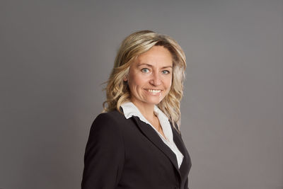 Portrait of young woman standing against gray background