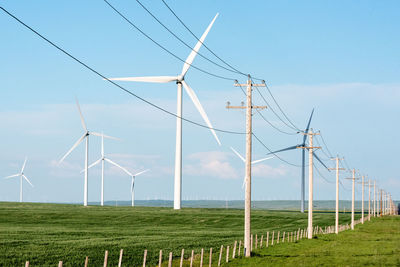 Windmills on field against clear sky