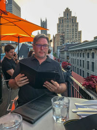 Man using mobile phone while sitting in city