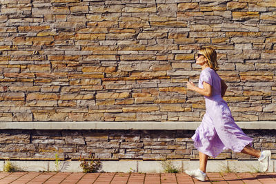 Side view of woman standing against brick wall