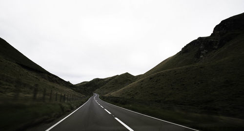 Empty road by mountains against sky