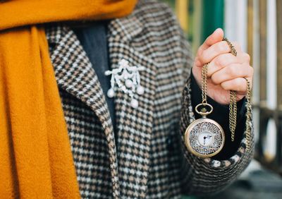 Midsection of person holding pocket watch