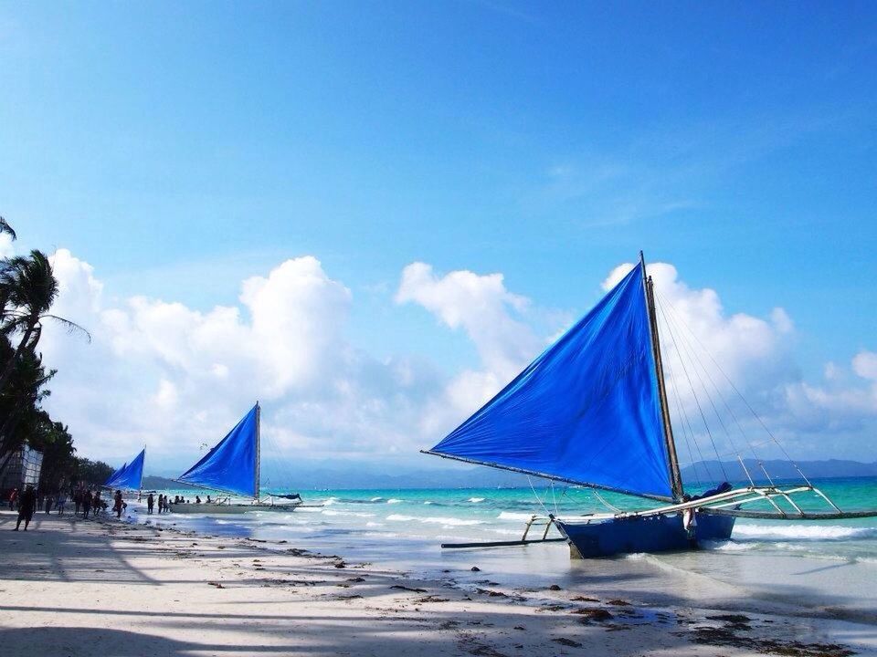 beach, sea, horizon over water, sky, blue, water, beach umbrella, sand, shore, parasol, cloud, flag, transportation, nautical vessel, cloud - sky, sunshade, vacations, boat, tranquility, umbrella