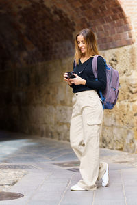 Full length of young man standing against wall