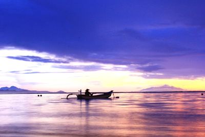 Silhouette people on sea against sky during sunset