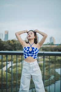 Portrait of young woman standing against sky