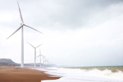 Wind turbines in sea against sky