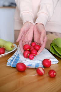 Cropped hand of woman picking fruits on table