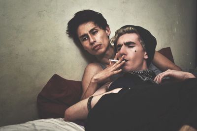 Gay couple smoking cigarette in bedroom