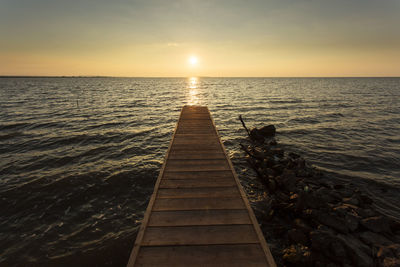 Pier over sea against sky during sunset