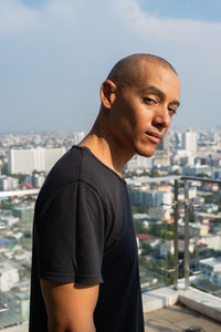 Side view of young man looking away against sky