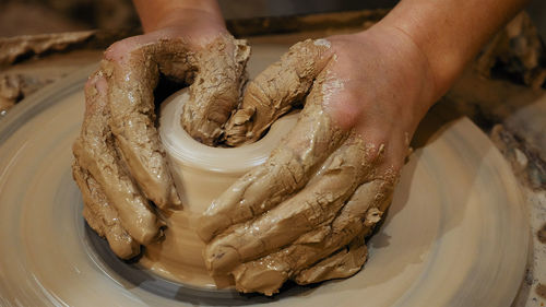 Cropped hands of craftsperson making clay product in pottery workshop