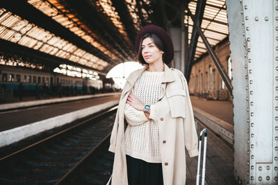 Casual young woman at the railway station awaits the arrival of the tr