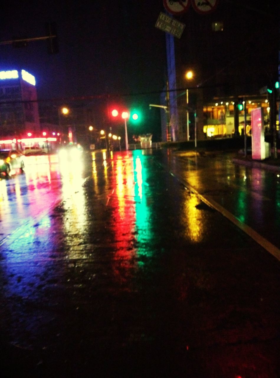 illuminated, night, street, lighting equipment, street light, city, building exterior, rain, wet, road, architecture, built structure, defocused, light - natural phenomenon, reflection, transportation, city street, city life, car, water