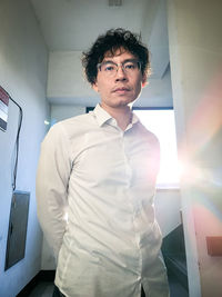 Portrait of young man standing against wall