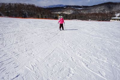 Rear view of person walking on snow covered field