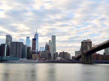 View of buildings at waterfront against cloudy sky