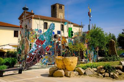 Multi colored sculpture on street by building against sky