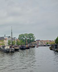 Sailboats moored on river against sky in city