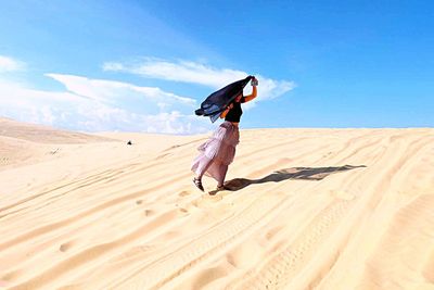 Woman walking on sand dune in desert
