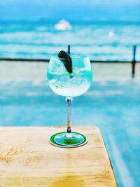 Close-up of drink on wooden table against swimming pool