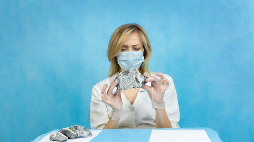 Portrait of a young woman holding blue wall