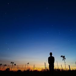 Silhouette man standing on field against sky at night