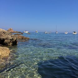 Boats in sea against clear sky