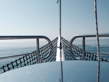 Metal railing by sea against clear sky